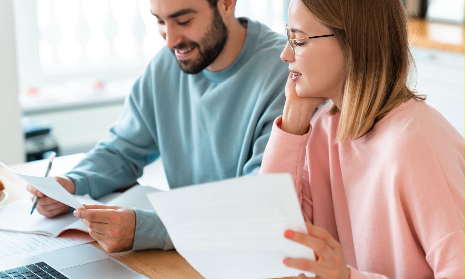 Man en vrouw samen aan tafel bezig met papieren. 